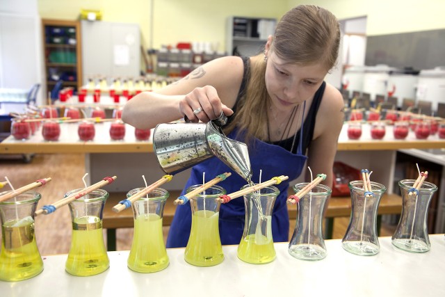 Eine Mitarbeiterin gießt flüssigen Kerzenwachs in ein Glas
